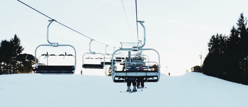 an adult and child, seen from behind, riding the ski lift during sunset