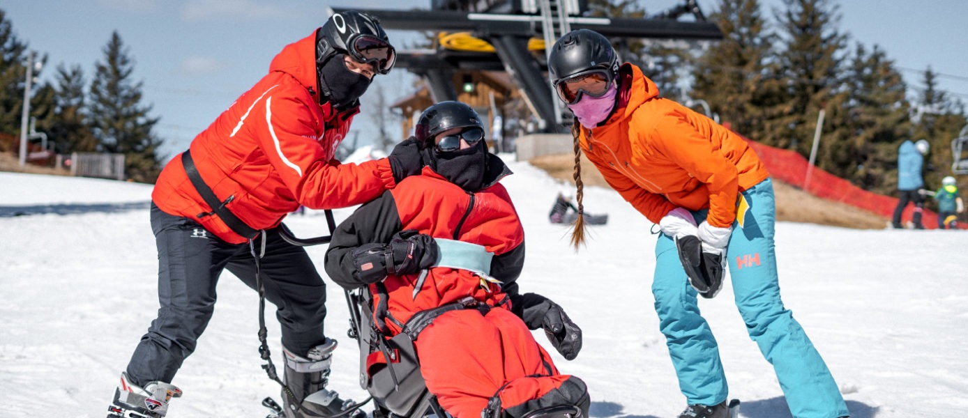 Two ski instructors helping a disabled skier