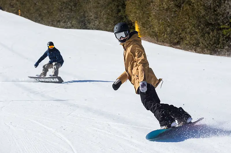 Two snowboarders going down a hill