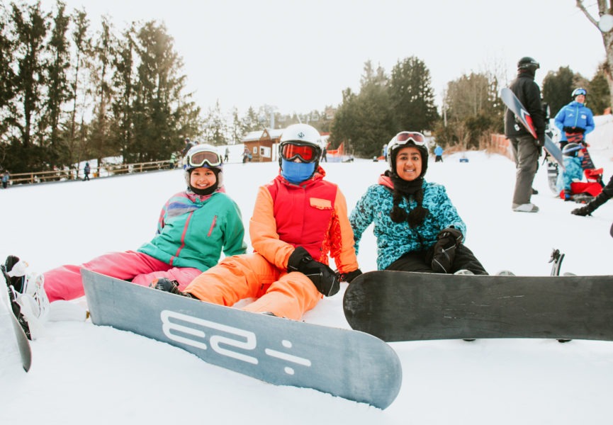 three snowboarders sitting in the snow