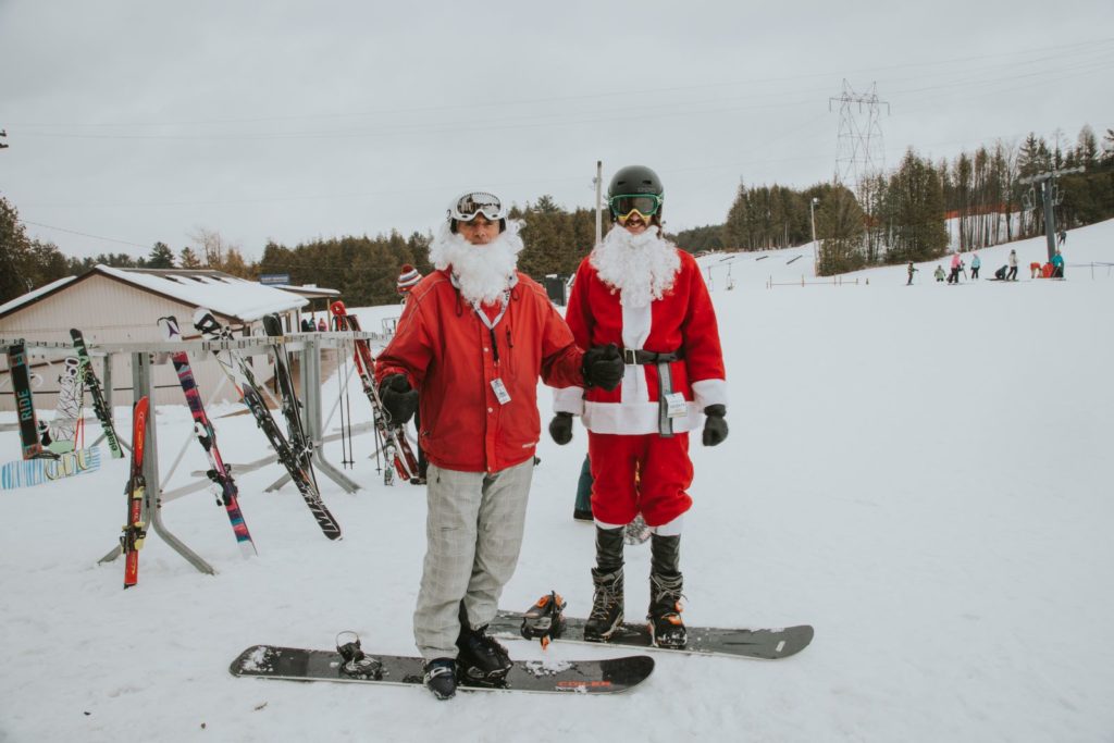 two men dressed as santa standing on snowboards