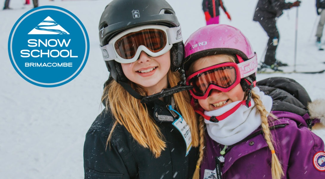 two girls, wearing ski helmets and goggles stand together and smile for the camera